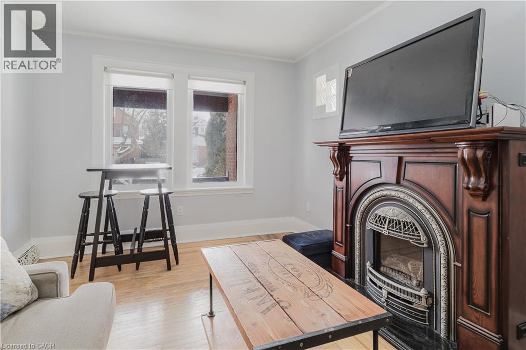 Living room with light wood-type flooring, a glass covered fireplace, and ornamental molding - 84 South Oval, Hamilton, ON - Indoor With Fireplace