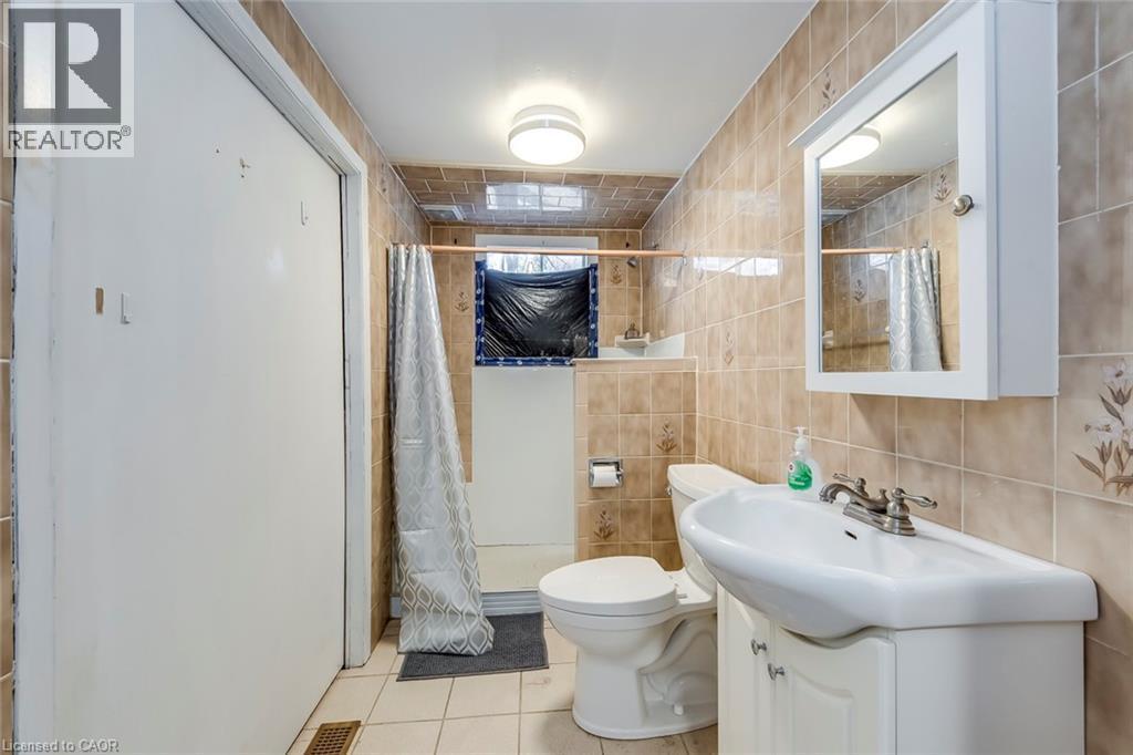 Full bath featuring vanity, a shower stall, tile walls, and light tile patterned floors - 142 Ewen Road, Hamilton, ON - Indoor Photo Showing Bathroom