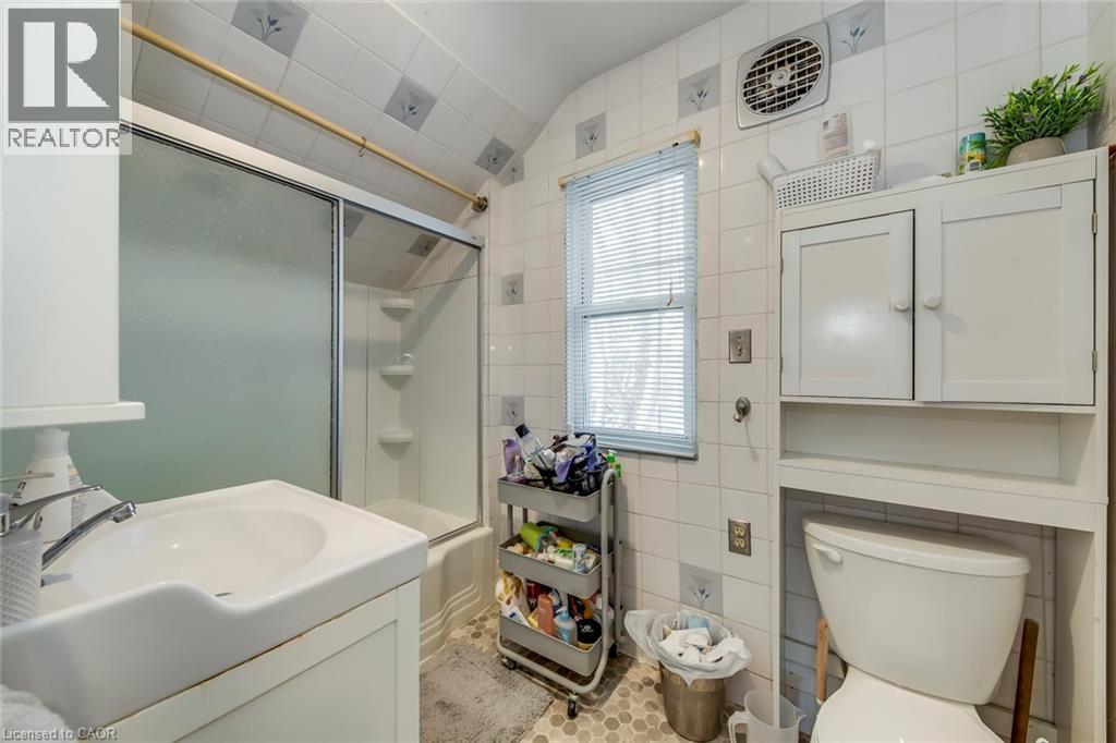 Full bath with vanity, tile walls, shower / bath combination with glass door, and vaulted ceiling - 142 Ewen Road, Hamilton, ON - Indoor Photo Showing Bathroom