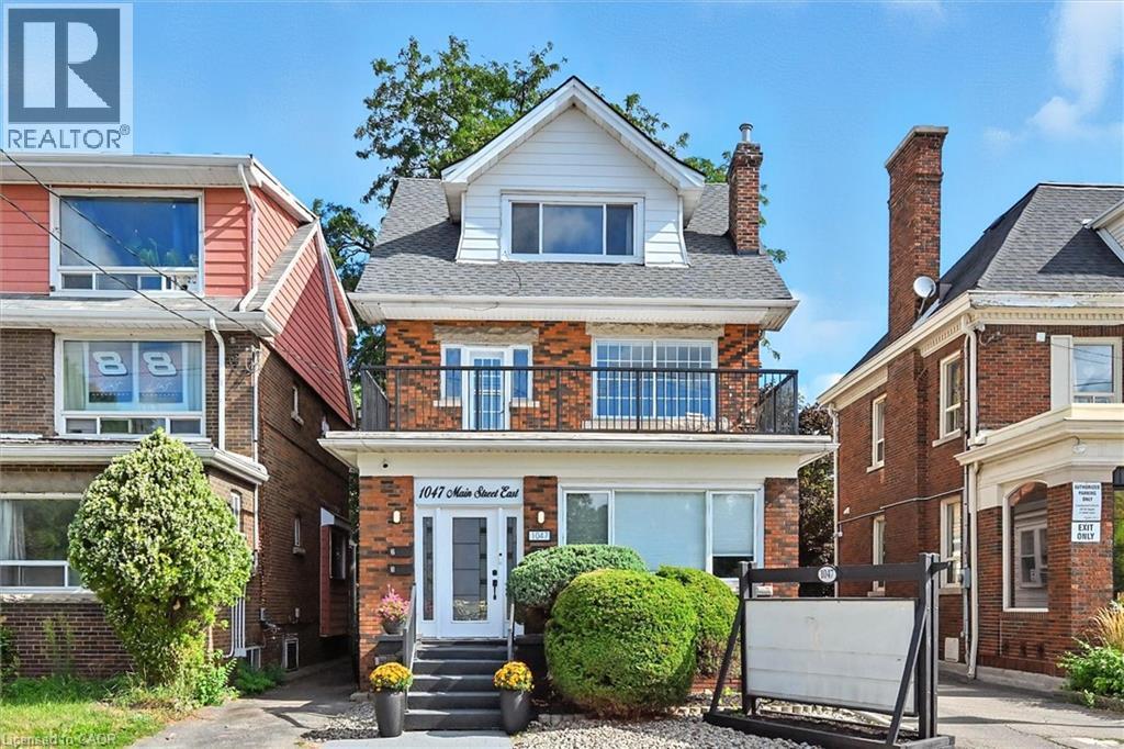View of front of home featuring a balcony, brick siding, and a shingled roof - 1047 Main Street E, Hamilton, ON - Outdoor With Facade