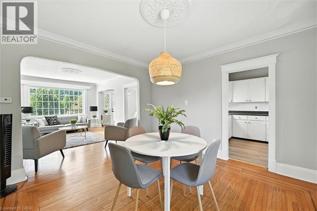 Dining room featuring arched walkways, crown molding, light wood-style floors, and radiator - 1047 Main Street E, Hamilton, ON - Indoor Photo Showing Dining Room