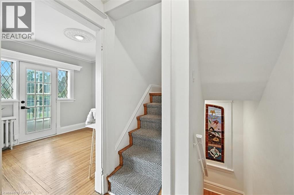 Stairway with ornamental molding, hardwood / wood-style floors, and radiator - 1047 Main Street E, Hamilton, ON - Indoor Photo Showing Other Room