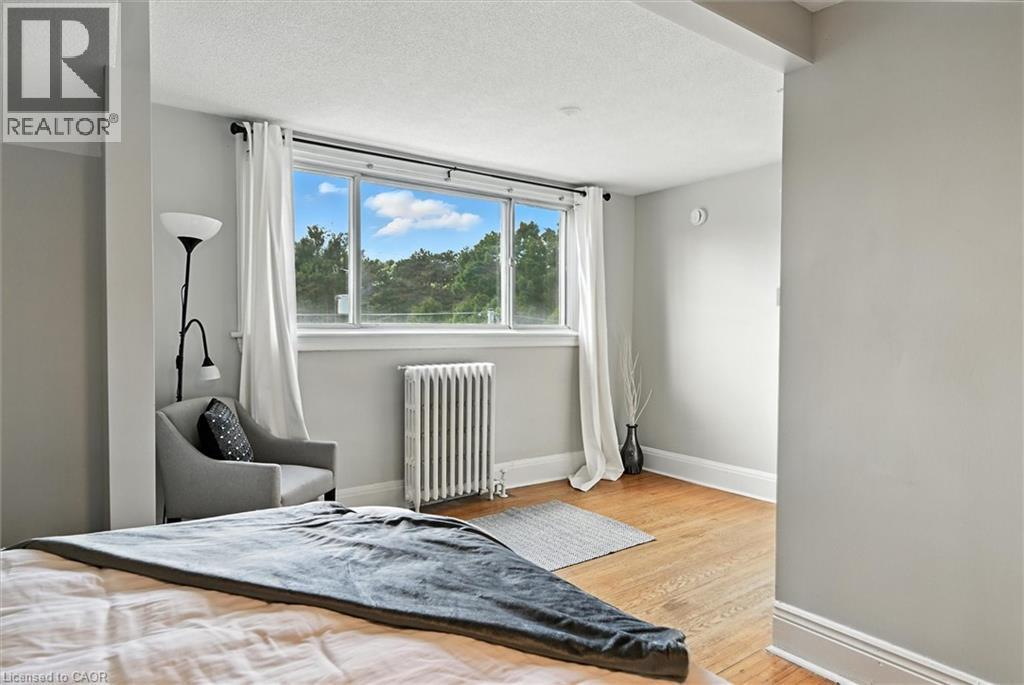 Bedroom featuring radiator heating unit, a textured ceiling, and light wood-style floors - 1047 Main Street E, Hamilton, ON - Indoor Photo Showing Bedroom