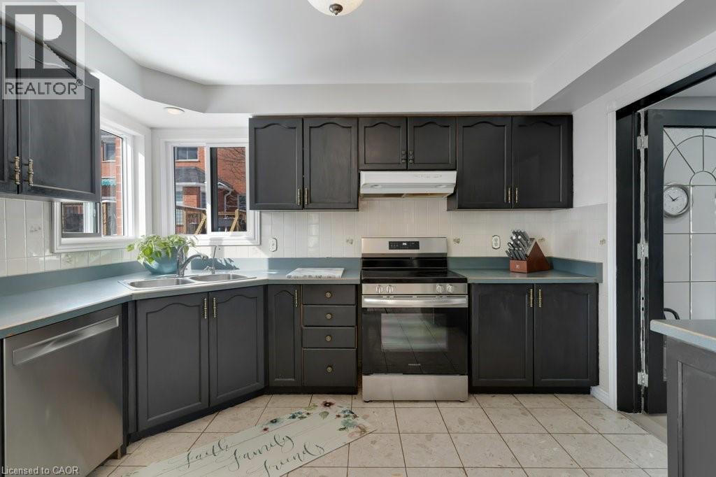 Kitchen with stainless steel appliances, decorative backsplash, light tile patterned floors, and light countertops - 148 Cowan Boulevard, Cambridge, ON - Indoor Photo Showing Kitchen With Double Sink