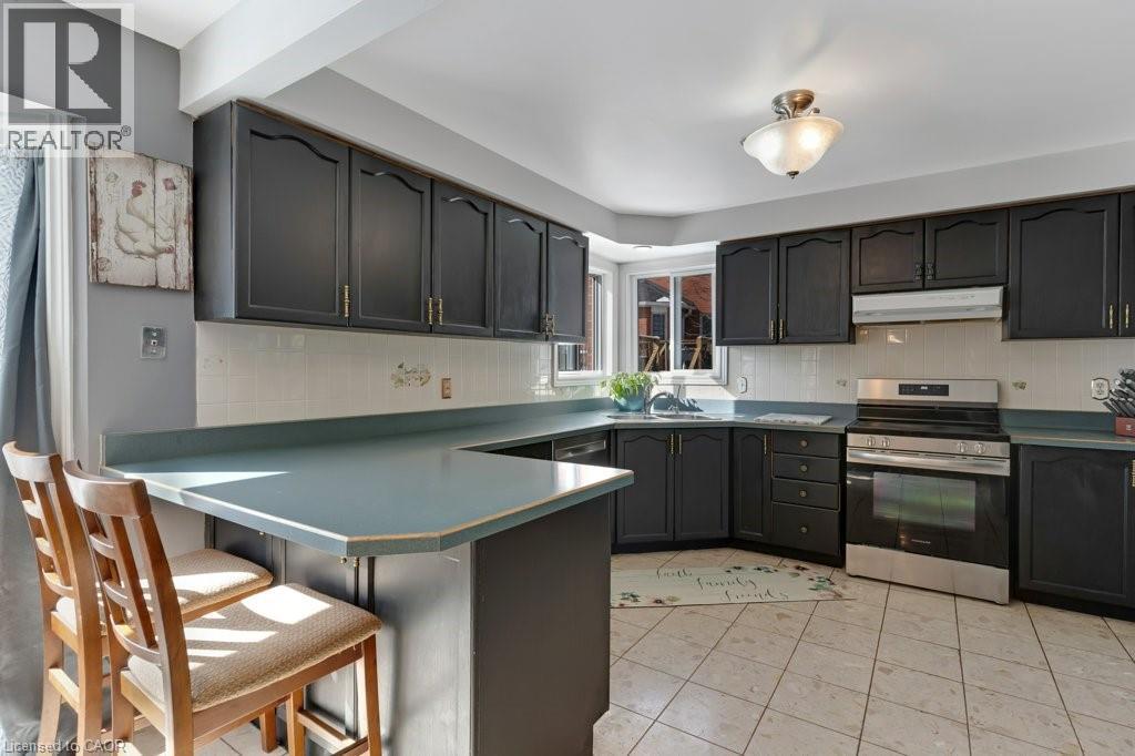 Kitchen featuring electric stove, a kitchen bar, decorative backsplash, a peninsula, and light tile patterned flooring - 148 Cowan Boulevard, Cambridge, ON - Indoor Photo Showing Kitchen