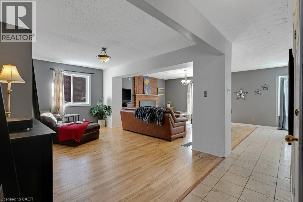 Living area featuring light wood-style flooring, a textured ceiling, a fireplace, and a chandelier - 148 Cowan Boulevard, Cambridge, ON - Indoor