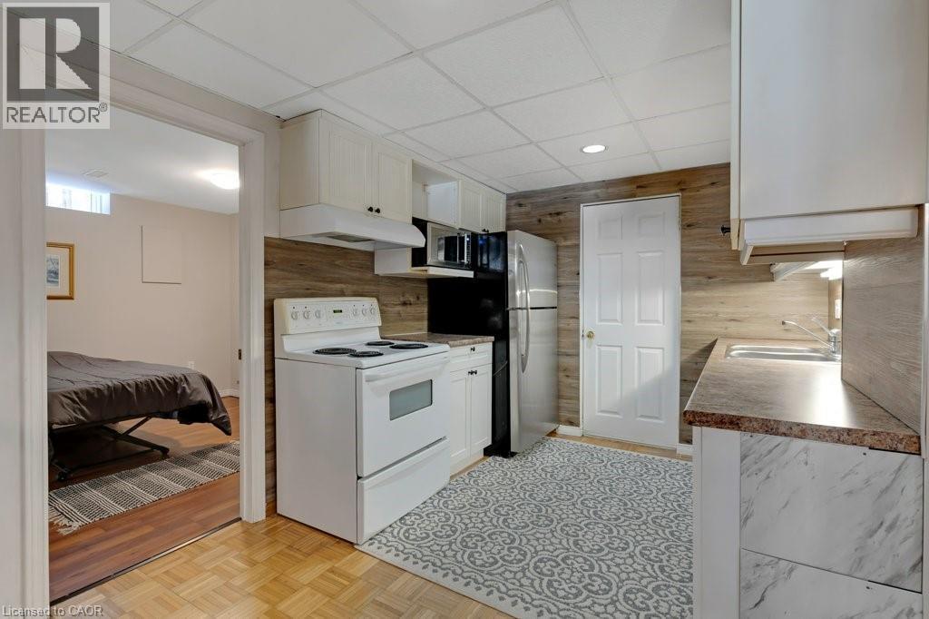Lower Kitchen featuring white range with electric cooktop, white cabinetry, parquet flooring, a drop ceiling, and light countertops - 148 Cowan Boulevard, Cambridge, ON - Indoor Photo Showing Kitchen
