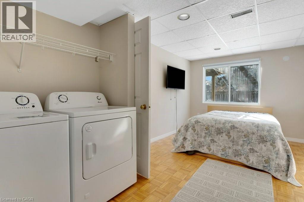 Lower level 2nd bedroom and Laundry room with parquet flooring, washer and dryer, and a paneled ceiling - 148 Cowan Boulevard, Cambridge, ON - Indoor Photo Showing Laundry Room