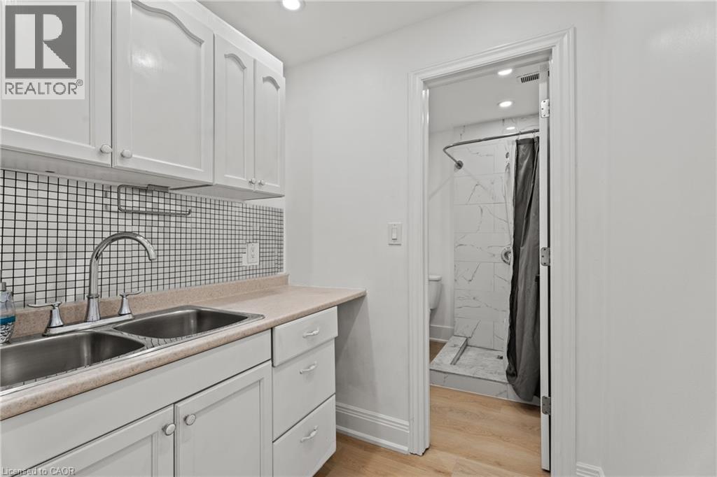 Kitchen featuring white cabinetry, light countertops, light wood-type flooring, backsplash, and recessed lighting - 93 John Street S, Hamilton, ON