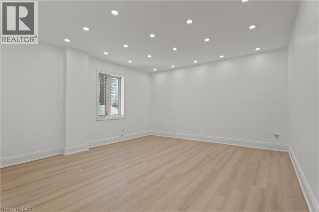 Empty room featuring light wood-style flooring and recessed lighting - 93 John Street S, Hamilton, ON