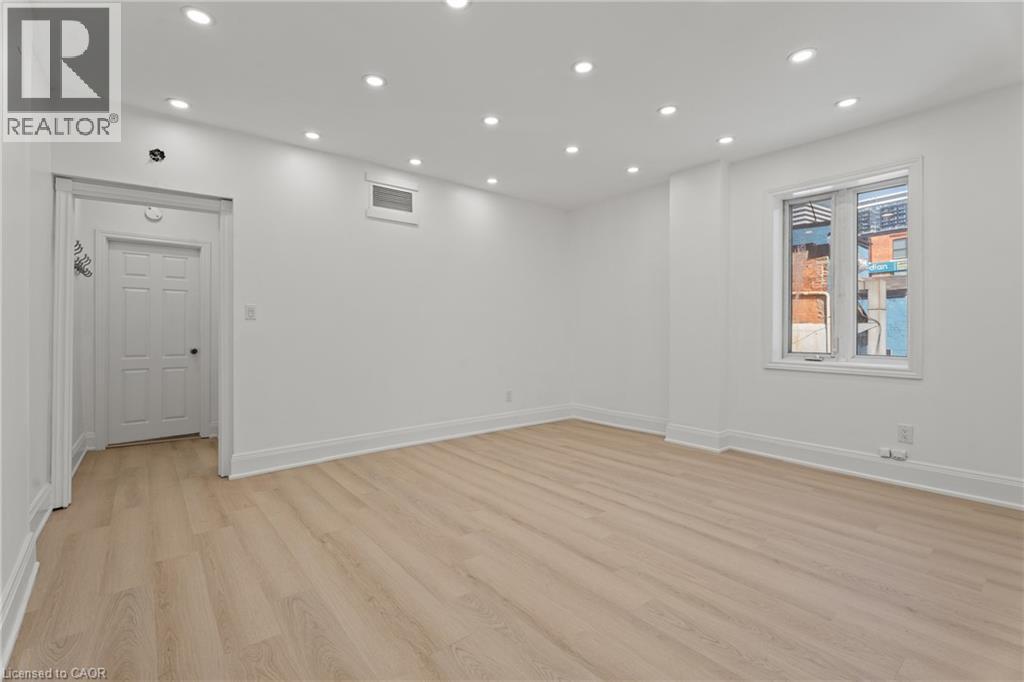 Empty room with light wood finished floors and recessed lighting - 93 John Street S, Hamilton, ON