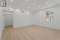 Empty room with light wood finished floors and recessed lighting -