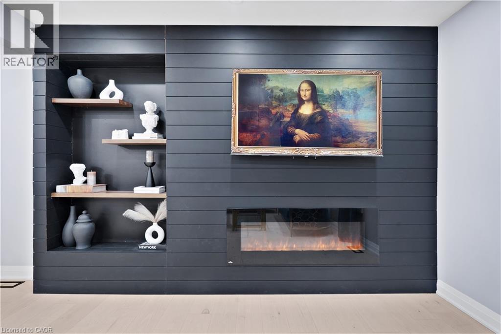 Detailed view of a fireplace, an accent wall, wood finished floors, and wood walls - 19 Broad Street, Brantford, ON - Indoor With Fireplace
