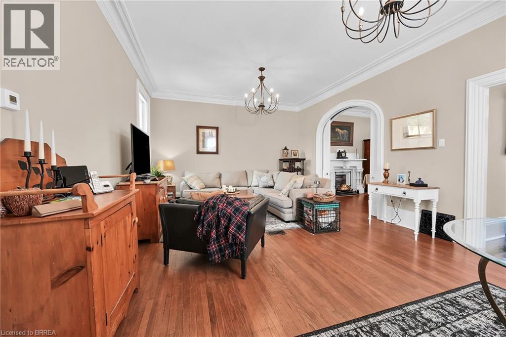 Living room with an inviting chandelier, ornamental molding, and hardwood / wood-style floors - 40 Locke Street S, Hamilton, ON - Indoor