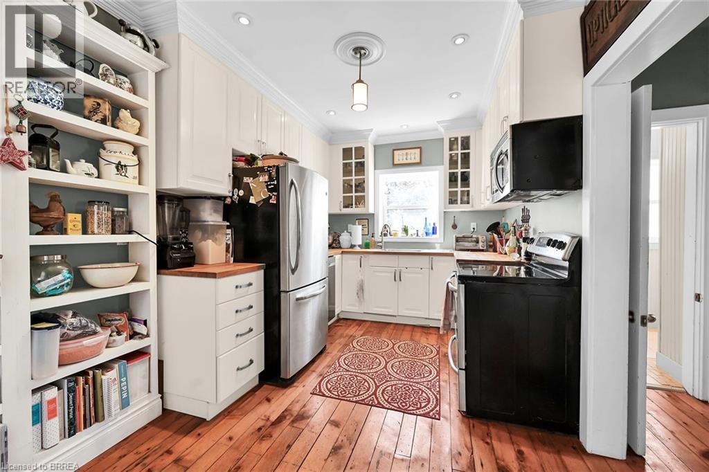 Kitchen with appliances with stainless steel finishes, white cabinetry, hanging light fixtures, ornamental molding, and light hardwood / wood-style flooring - 40 Locke Street S, Hamilton, ON - Indoor Photo Showing Kitchen