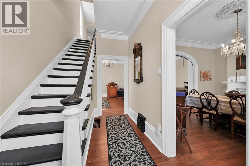 Stairway featuring an inviting chandelier, ornamental molding, and hardwood / wood-style floors - 40 Locke Street S, Hamilton, ON - Indoor Photo Showing Other Room