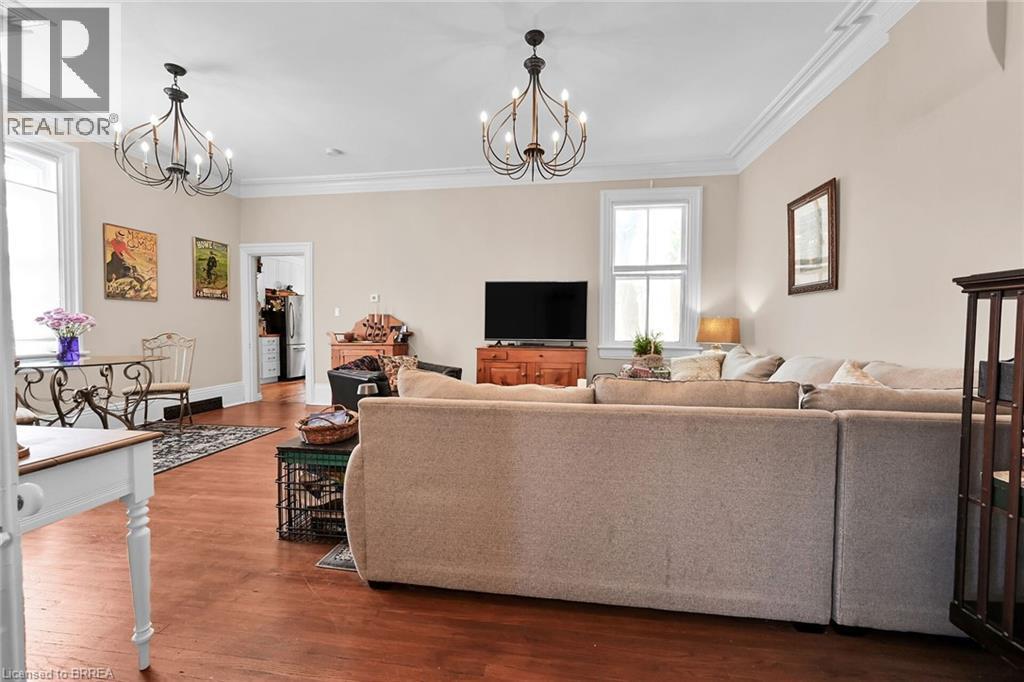 Living room with hardwood / wood-style flooring, ornamental molding, and a notable chandelier - 40 Locke Street S, Hamilton, ON - Indoor Photo Showing Living Room