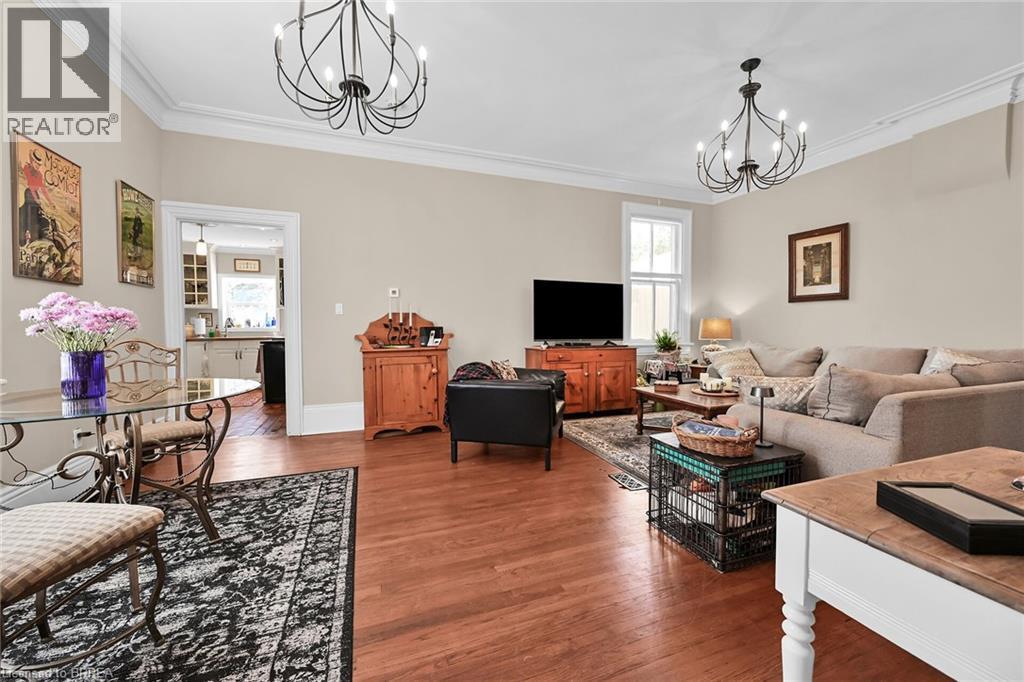Living room with wood-type flooring, a notable chandelier, and crown molding - 40 Locke Street S, Hamilton, ON - Indoor Photo Showing Living Room