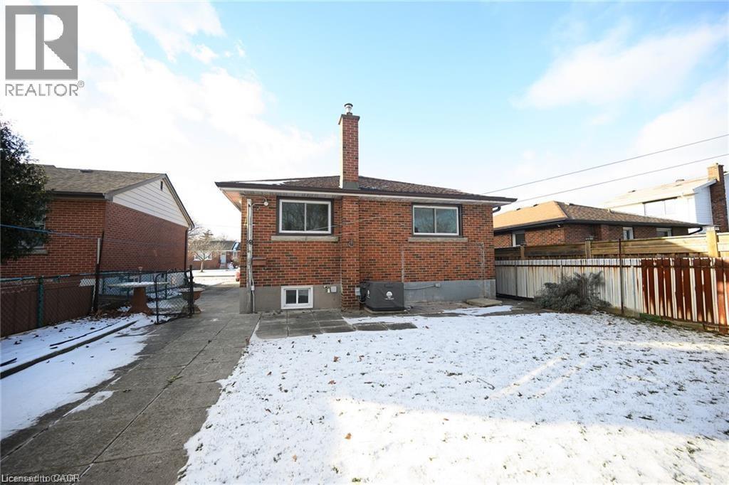 Snow covered back of property featuring a chimney, brick siding, and a patio - 325 East 16Th Street, Hamilton, ON - Outdoor