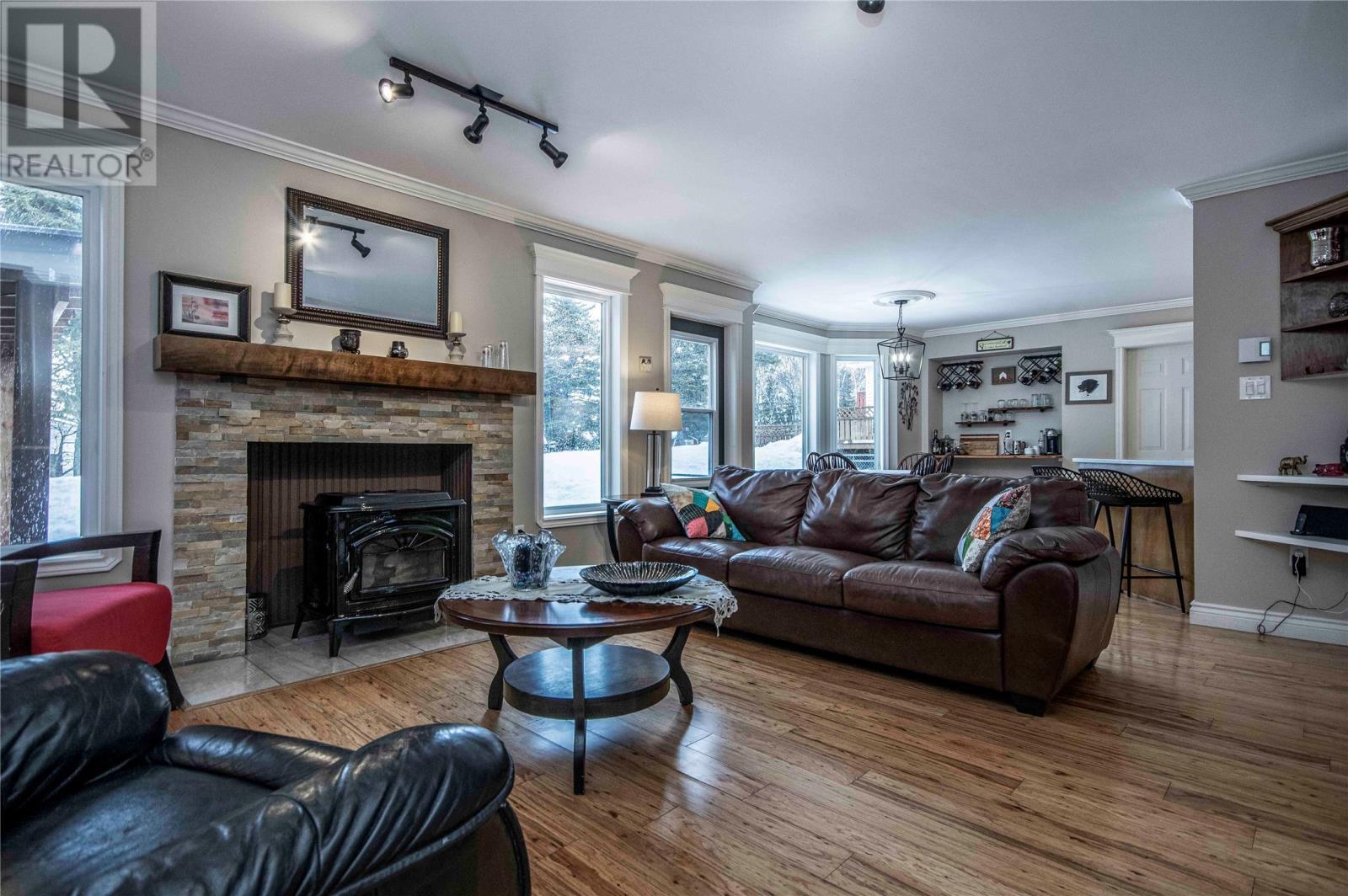 Rooms at back of house open to patio and covered BBQ area - 34 Blackstrap Path, Conception Bay South, NL - Indoor Photo Showing Living Room With Fireplace