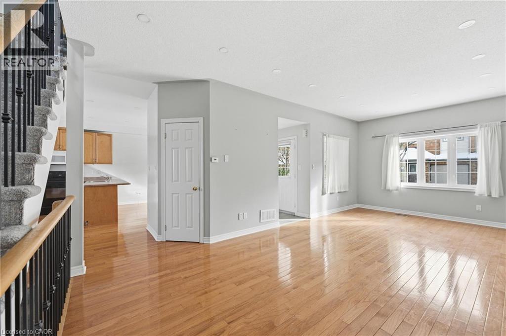 Unfurnished living room featuring stairway, light wood-type flooring, and a textured ceiling - 100 Beddoe Drive Unit# 25, Hamilton, ON - Indoor Photo Showing Other Room