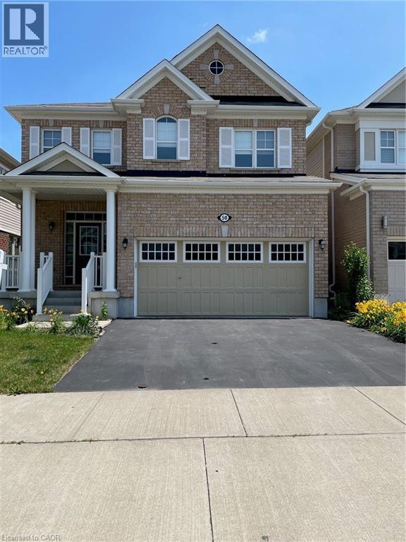 View of front of home featuring brick siding, covered porch, concrete driveway, and an attached garage - 50 Shoreacres Drive, Kitchener, ON - Outdoor With Facade