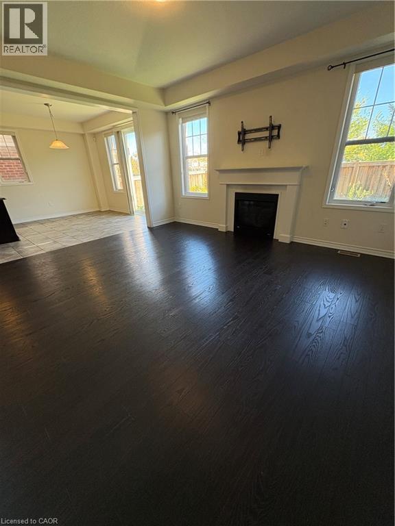 Unfurnished living room with plenty of natural light, a fireplace, and dark wood-style flooring - 50 Shoreacres Drive, Kitchener, ON - Indoor With Fireplace