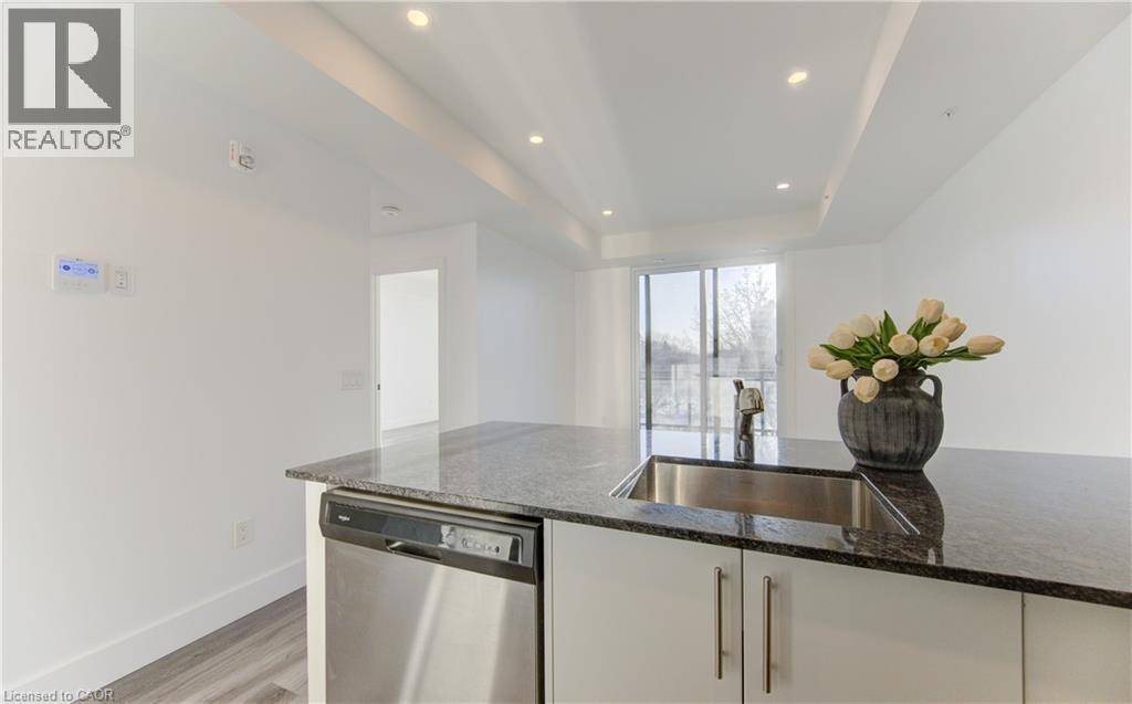 Kitchen featuring white cabinets, dishwasher, dark stone countertops, recessed lighting, and light wood-style flooring - 103 Roger Street Unit# 310, Waterloo, ON - Indoor Photo Showing Kitchen