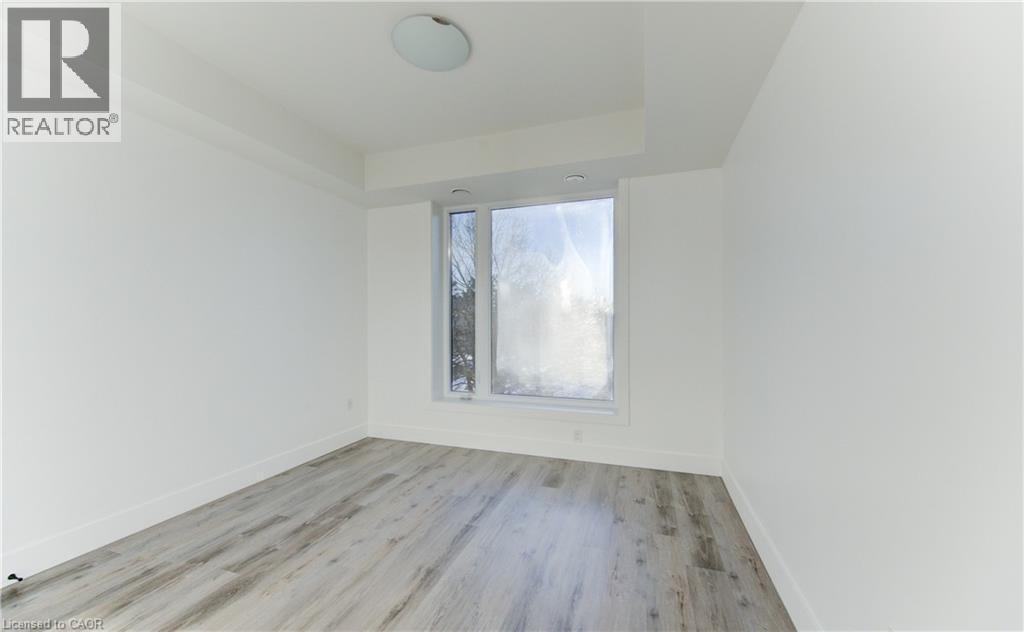 Spare room with light wood-style floors and a raised ceiling - 103 Roger Street Unit# 310, Waterloo, ON - Indoor Photo Showing Other Room