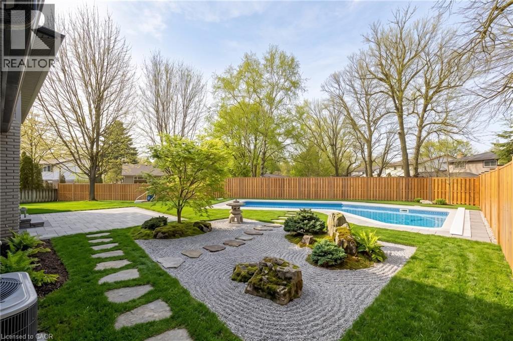 Expansive backyard featuring a blue-tiled swimming pool and surrounding gray concrete patio - 361 Coleridge Place, Waterloo, ON - Outdoor With In Ground Pool With Backyard