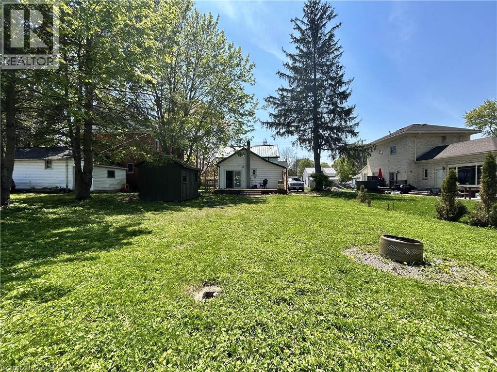 Expansive rear lawn featuring mature trees, a detached shed, and a private deck area - 101 John Street E, Wingham, ON - Outdoor