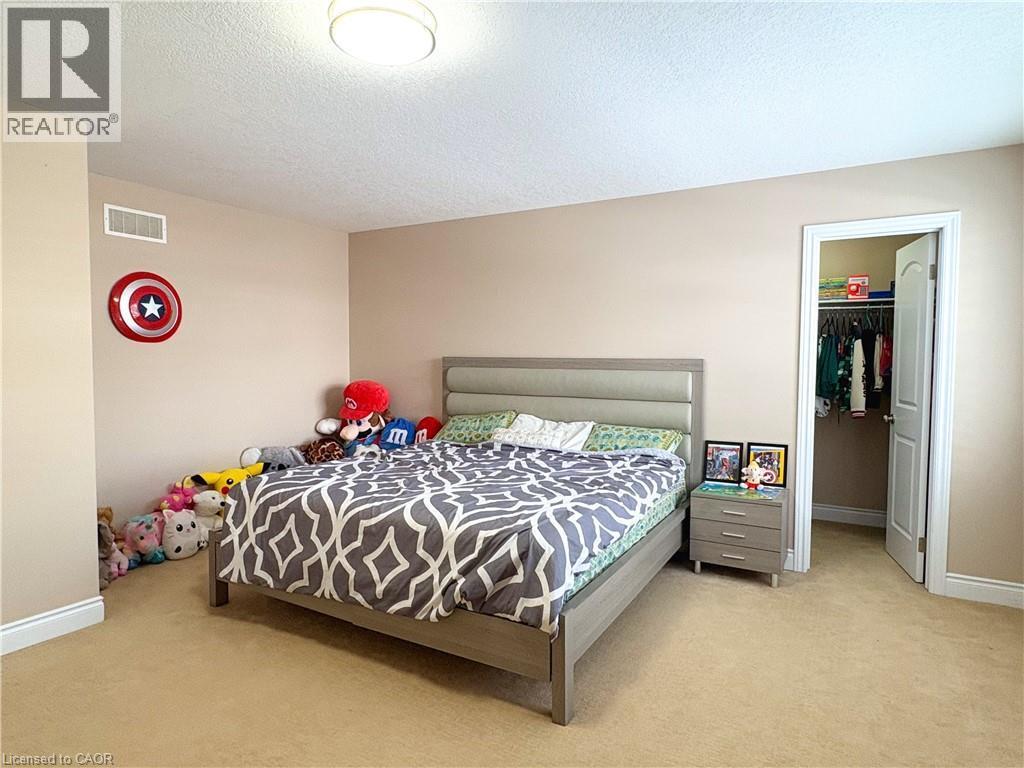 Carpeted bedroom with a spacious closet, a textured ceiling, and a closet - 34 Watervale Drive Unit# Upper, Kitchener, ON - Indoor Photo Showing Bedroom