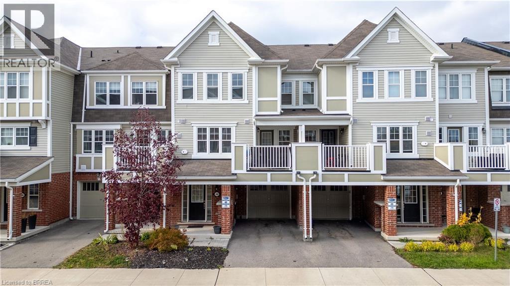 View of front of house featuring driveway, a residential view, a garage, brick siding, and a balcony - 143 Ridge Road Unit# 48, Cambridge, ON - Outdoor With Facade