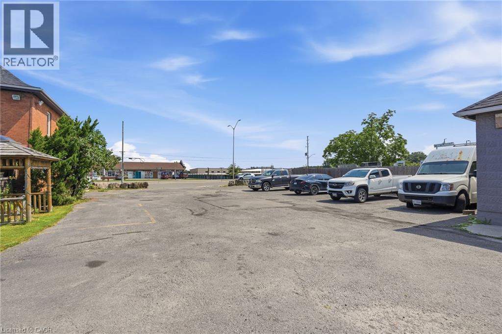 Asphalt parking lot featuring a brick building facade and a wooden gazebo - 1360 Rymal Road E, Hamilton, ON