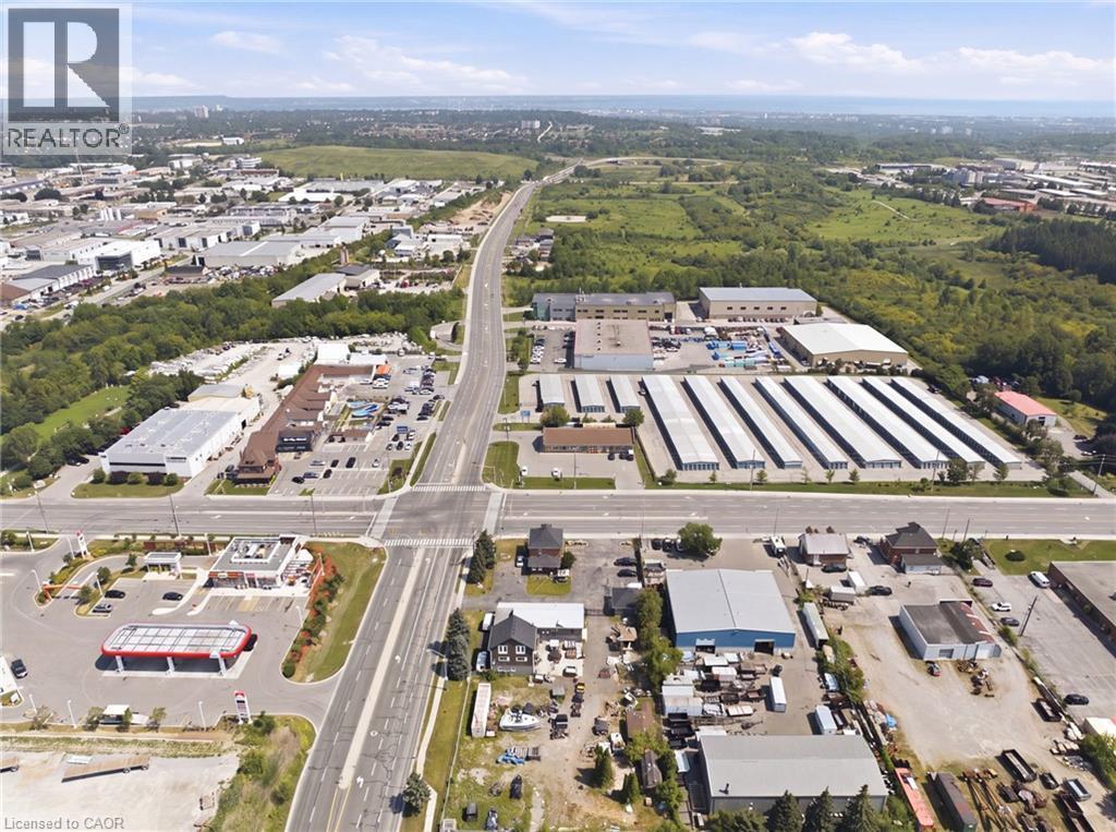 Aerial perspective showcasing expansive commercial development with multiple buildings, paved roadways, and significant land area - 1360 Rymal Road E, Hamilton, ON
