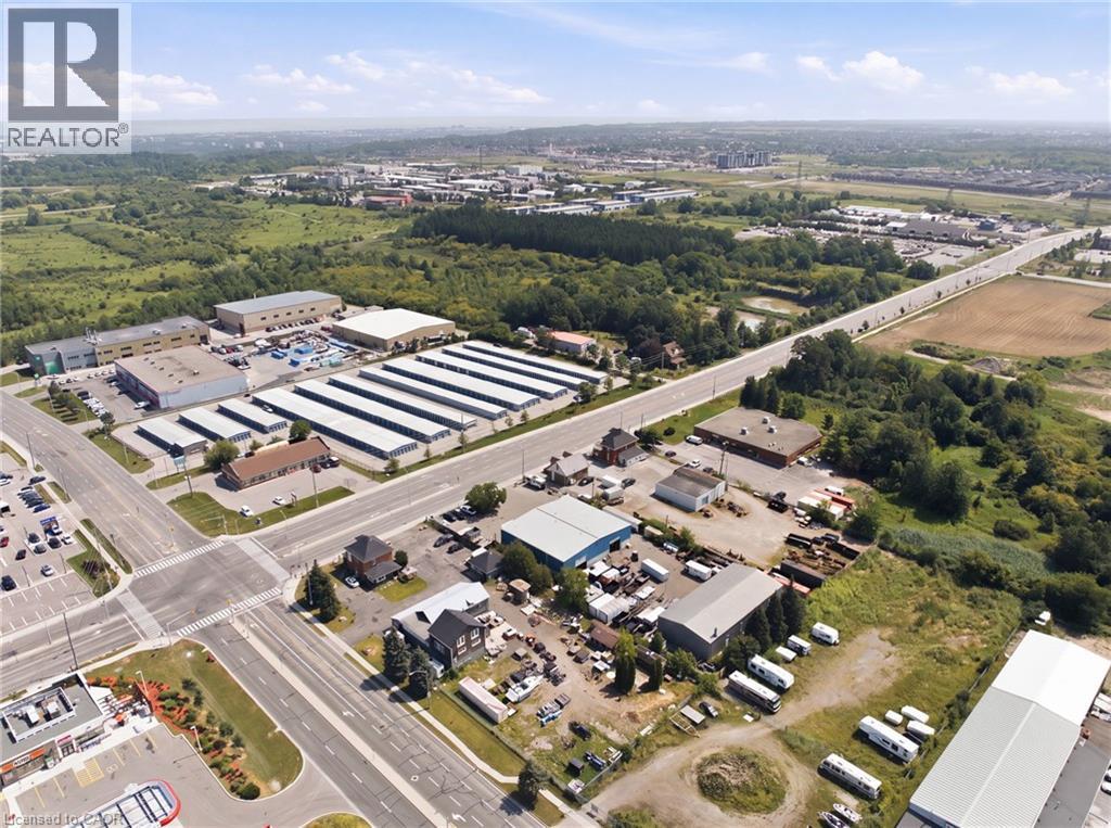 Aerial perspective showcasing a commercial property with multiple buildings and a large paved lot - 1360 Rymal Road E, Hamilton, ON