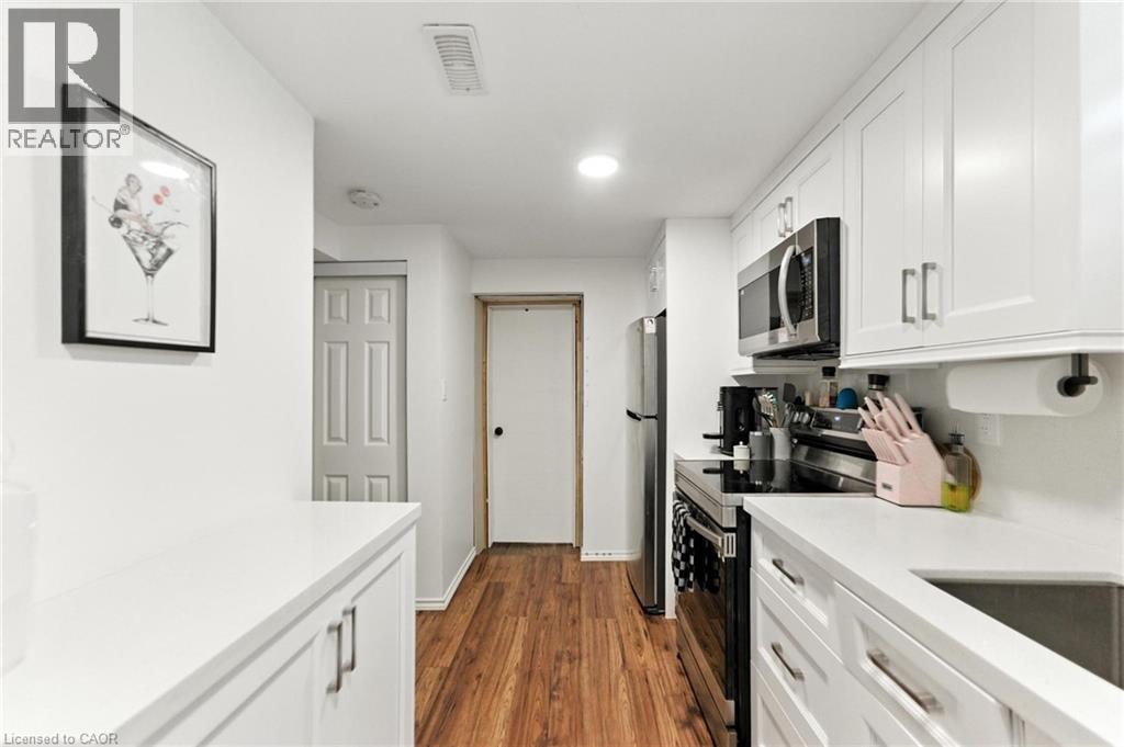 Kitchen with stainless steel appliances, white cabinets, dark wood-style floors, and recessed lighting - 90 Toby Crescent Unit# Lower, Hamilton, ON - Indoor Photo Showing Kitchen