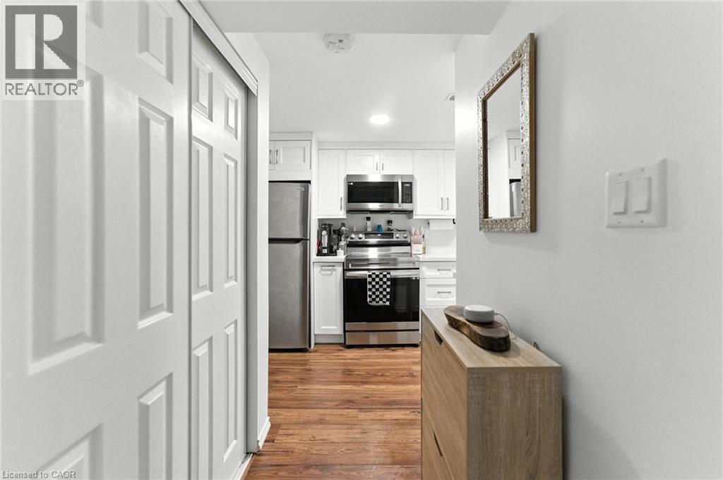 Hallway to Kitchen featuring white cabinets, stainless steel appliances, wood finished floors, and recessed lighting - 90 Toby Crescent Unit# Lower, Hamilton, ON - Indoor