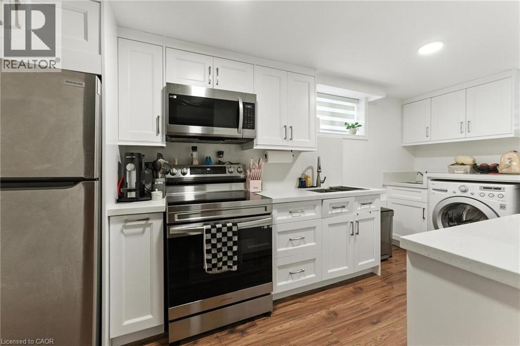 Kitchen with stainless steel appliances, washer / dryer, white cabinetry, dark wood finished floors, and recessed lighting - 90 Toby Crescent Unit# Lower, Hamilton, ON - Indoor Photo Showing Kitchen