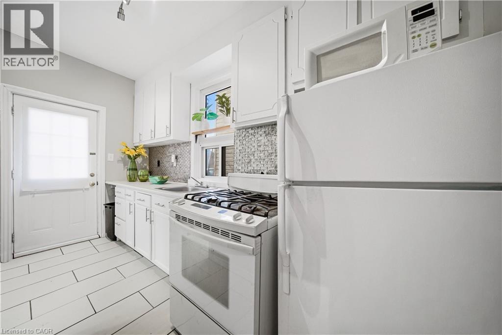 Kitchen (Main Floor). Gas Stove, Ceramic Back-splash and Flooring, Back Door Leads to Yard & Parking - 107 Queen Street S, Hamilton, ON - Indoor Photo Showing Kitchen