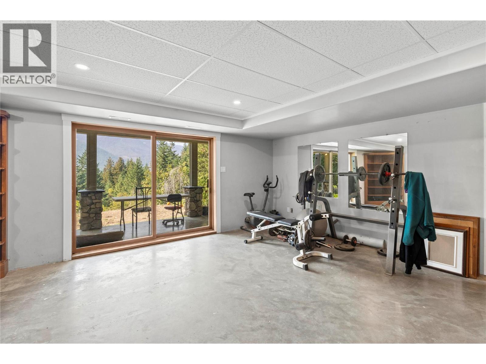 Lower level Family Room with sliders to covered concrete deck - 1403 Notch Hill Road, Sorrento, BC - Indoor Photo Showing Gym Room