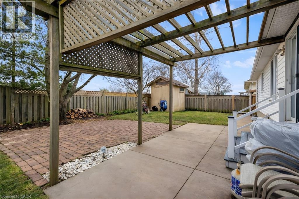 Fenced backyard featuring a patio area, a pergola, and a storage unit - 65 Thistlemoor Drive, Caledonia, ON - Outdoor