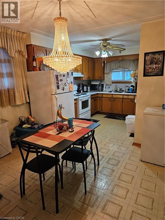 Kitchen with light floors, white appliances, wood finish cabinets, light countertops, and suspended lighting - 197 Craigroyston Road, Hamilton, ON - Indoor