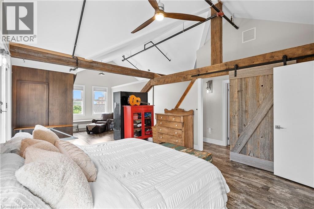 Bedroom with a barn door, wood finished floors, and ceiling fan - 25 Concession Street Unit# 201, Cambridge, ON - Indoor Photo Showing Bedroom