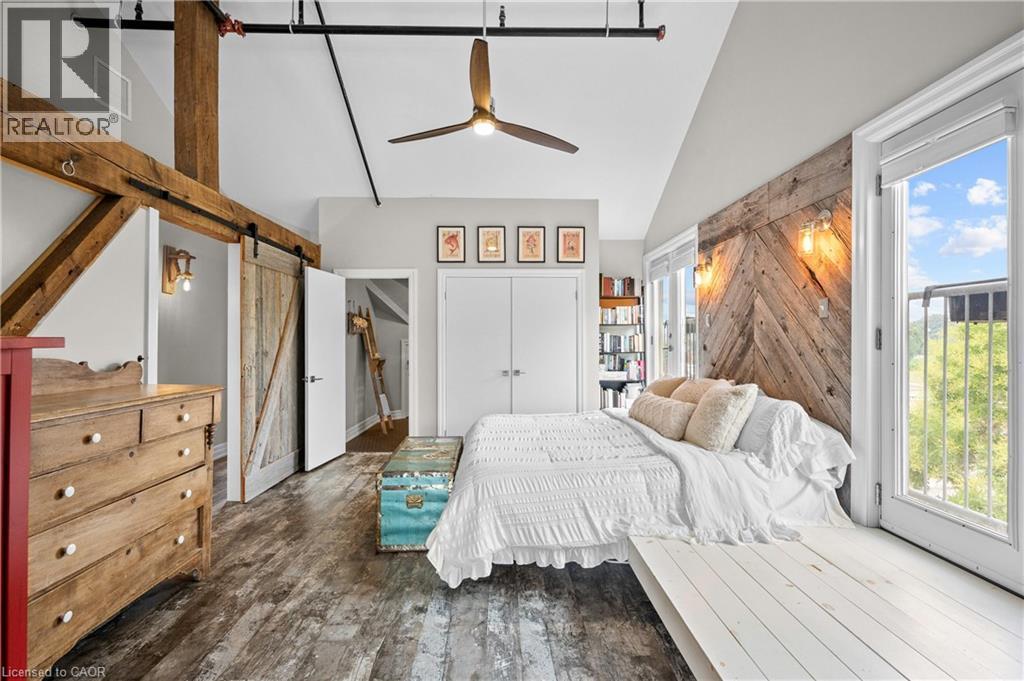 Bedroom featuring a barn door, lofted ceiling, dark wood-type flooring, a ceiling fan, and access to outside - 25 Concession Street Unit# 201, Cambridge, ON - Indoor Photo Showing Bedroom