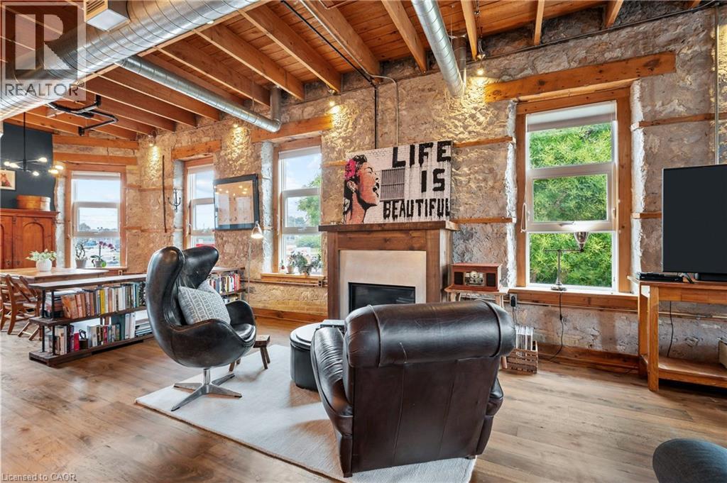 Living area with wood-type flooring, a fireplace, and a wooden ceiling with exposed beams - 25 Concession Street Unit# 201, Cambridge, ON - Indoor With Fireplace