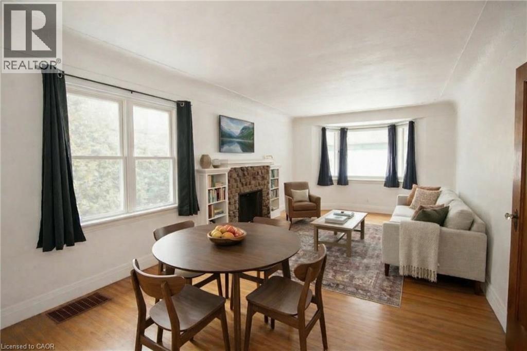 Digitally staged, Dining space with a stone fireplace and wood finished floors - 90 Osler Drive, Dundas, ON - Indoor