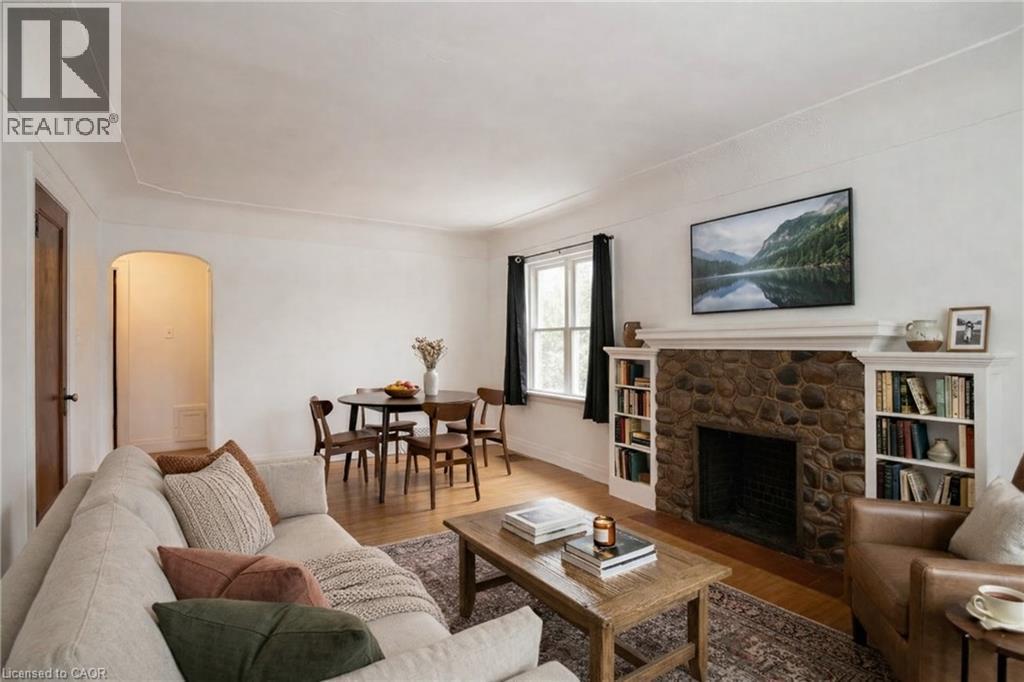 Digitally staged, Living room with arched walkways, wood finished floors, and a stone fireplace - 90 Osler Drive, Dundas, ON - Indoor Photo Showing Living Room With Fireplace