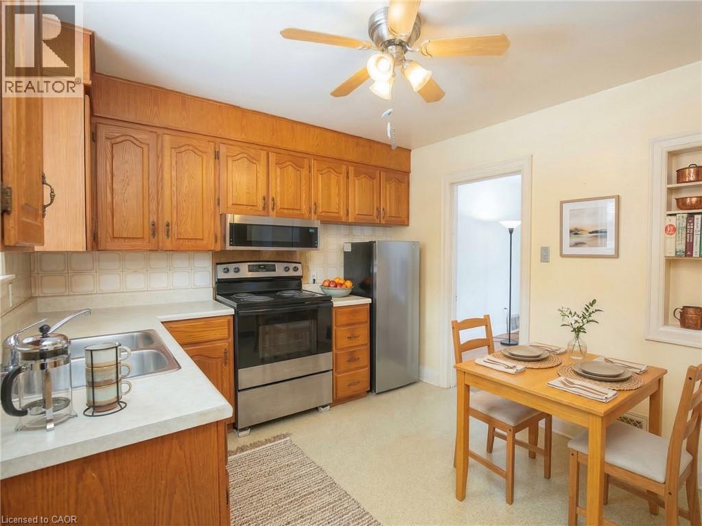 Digitally staged Kitchen with stainless steel appliances, light countertops, wood finish cabinets, ceiling fan, and decorative backsplash - 90 Osler Drive, Dundas, ON - Indoor Photo Showing Kitchen With Double Sink