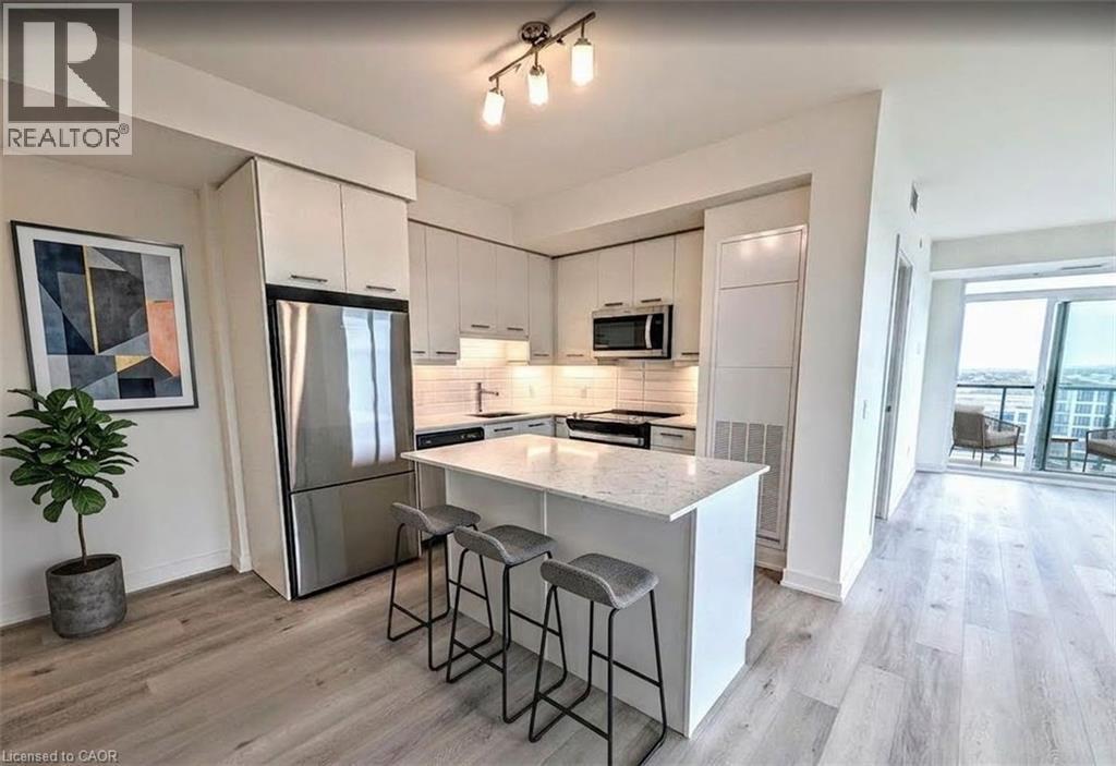 Kitchen featuring stainless steel appliances, a breakfast bar area, white cabinetry, and light wood-style flooring - 385 Winston Road Unit# 1311, Grimsby, ON - Indoor Photo Showing Kitchen With Stainless Steel Kitchen With Upgraded Kitchen
